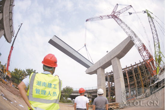 红易-沪昆跨线桥跨沪昆高速公路主跨架梁施工现场，一节节钢箱梁被吊起安装。（记者 方阳 摄）